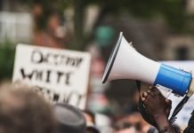 Photo of a Black protestor holding a megaphone.