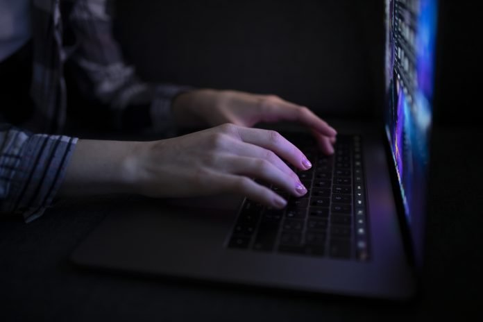 A woman's hands typing on a laptop