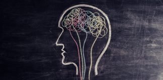 Photo of a hand using chalk to draw a head with spirals inside the brain