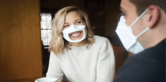 Photo of a woman wearing a transparent face mask while talking to a man wearing a facial mask.