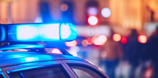 Photo of a police car with the siren lights lit up.