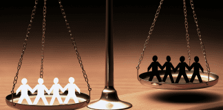 Photo of a scale depicting White stick figures on one side and Black stick figures on the other side.
