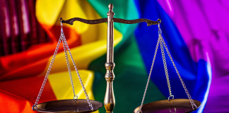 Photo of a scale in front of a LGBTQ pride flag