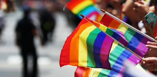 Photo of people holding LGBTQ Pride flags during a Pride Month march.