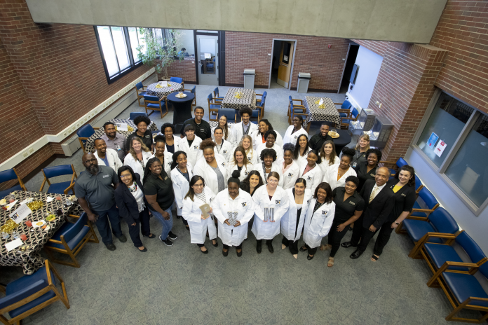 Members of the inaugural Vet Up! College graduating class at Purdue University College of Veterinary Medicine (PVM) don their new white coats alongside PVM teaching assistants, faculty, and staff, including Assistant Dean for Inclusive Excellence Latonia Craig (second row, far left) and Dean Willie Reed (second row, far right) at a special graduation ceremony in the PVM Medical Library in West Lafayette, Indiana on June 28, 2019.