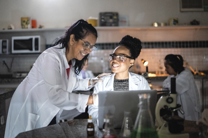 GettyImages-1356640061 two women talking in a science lab