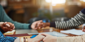 group of diverse people holding hands over a table