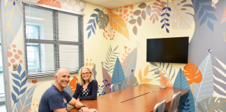 Two people in wheelchairs sit at a conference table