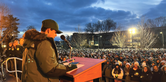 Michigan State University student Joseph Kesto stands at a podium in front of a crowd