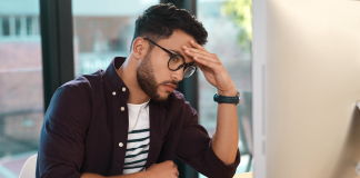 Man sitting in front of computer rests his head on his hand
